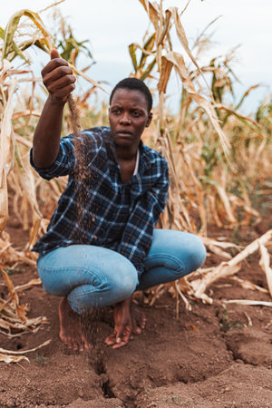 African farmer dropping seeds in dry soil during droughtの写真素材