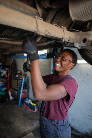 Young female mechanic working under a car using a wrenchの写真素材