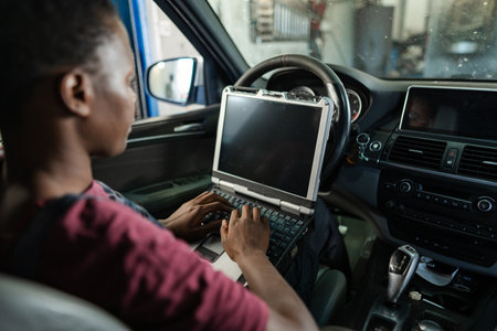 Car mechanic running diagnostics on a vehicle using a laptopの写真素材