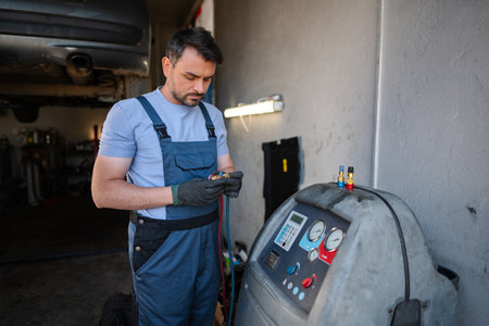 Car mechanic using air conditioning charging machine in a workshopの写真素材