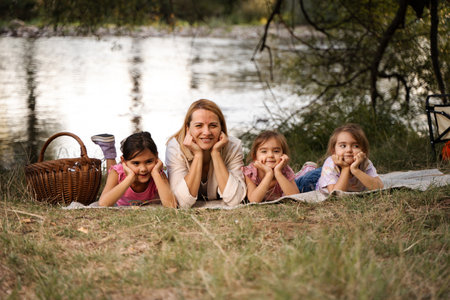 Mother and daughters enjoying picnic by the river