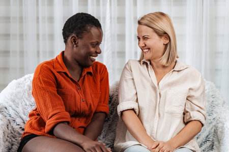Two young women laughing and talking at homeの写真素材