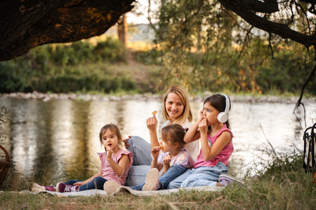 Mother having picnic with her three daughters by the riverの写真素材