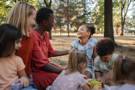 Diverse group of preschool children enjoying playtime with their teachers in a parkの写真素材