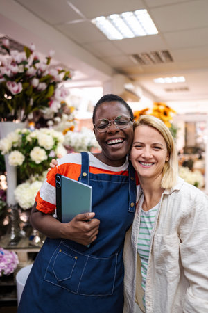 Two happy female florists embracing in a flower shopの写真素材