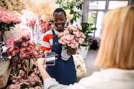 Florist accepting payment via smartphone from customer in flower shopの写真素材