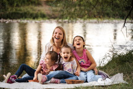 Mother and daughters laughing together during a picnic by the river