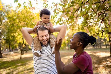 Joyful family moment in a sunlit park during autumnの写真素材