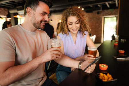 Couple enjoying drinks and social media at the bar counterの写真素材