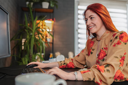 Smiling businesswoman working from home office using desktop computerの写真素材