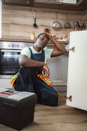 Tired handyman resting after fixing kitchen cabinetsの写真素材