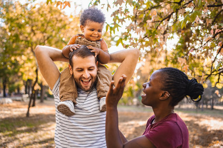 Boy in the arms of his parents in the parkの写真素材