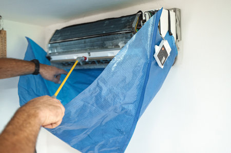 The technician are cleaning the air conditioner by spraying waterの写真素材