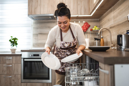 Woman loading the dishwasher in the kitchenの写真素材