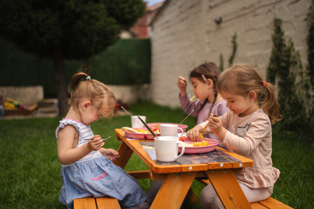 Joyful afternoon of children enjoying snacks in a sunny gardenの写真素材