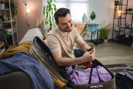 Man packing suitcase on sofa at home getting ready for holiday travel