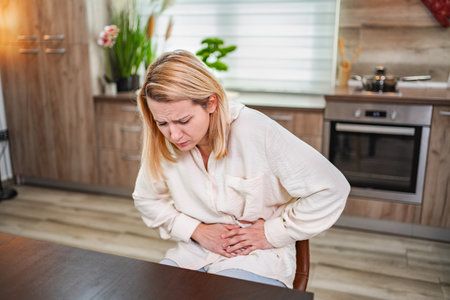 Stomach pain leads to discomfort during a quiet morning at homeの写真素材