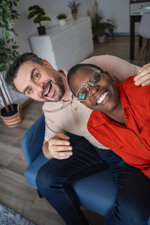 Interracial Couple Taking a Selfie on the Couch at Home, Smiling at the Camera