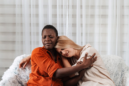 Two Young Women Embracing and Showing Support on a Sofaの写真素材