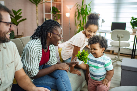 Joyful children share plants in a cozy living roomの写真素材