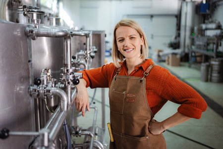 Woman brewer standing in microbrewery smiling at cameraの写真素材