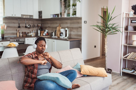 Young woman enjoying music with headphones in living roomの写真素材