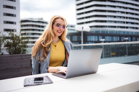 Businesswoman working on laptop on urban building rooftopの写真素材