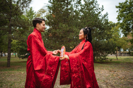 Interracial couple celebrating traditional Chinese wedding outdoorsの写真素材