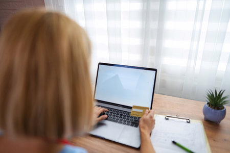 Woman making online payment using laptop and credit card at homeの写真素材