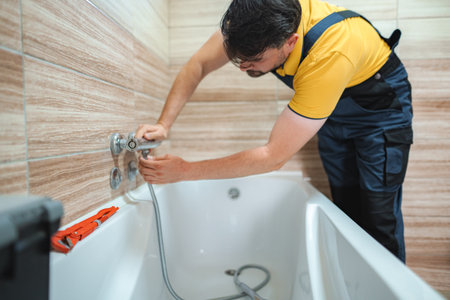 Plumber Installing Faucet on Bathtub in Bathroomの写真素材