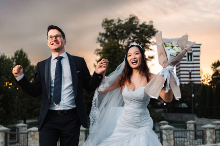 Happy interracial wedding couple celebrating marriage outdoorsの写真素材