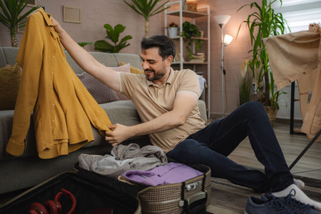 Man packing clothes for holiday trip at homeの写真素材