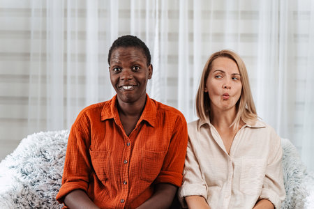 Two female friends making funny faces and smiling at cameraの写真素材