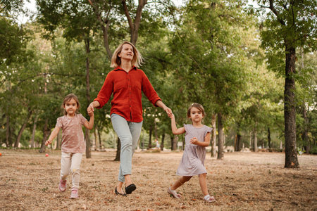 Mother and daughters running in the park holding hands