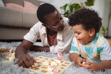Mother and son playing with alphabet puzzle on carpetの写真素材
