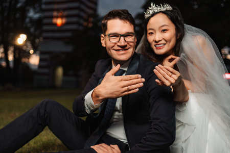 Interracial wedding couple showing engagement rings after ceremonyの写真素材