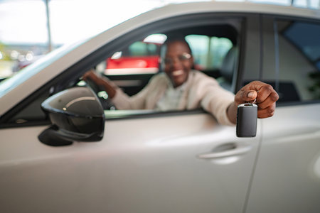 Happy man holding new car key at dealershipの写真素材
