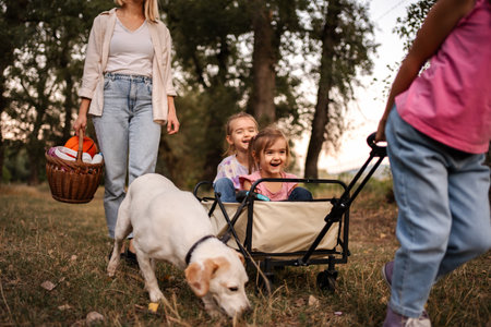 Family enjoying a walk in the woods with their dog pulling a wagon with two little girlsの写真素材