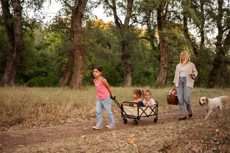 Family enjoying a walk in the woods with their dog and a wagonの写真素材