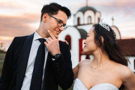 Interracial couple celebrating wedding day, looking at each other romanticallyの写真素材