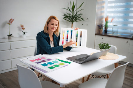 Woman showing color palette during video call at home officeの写真素材