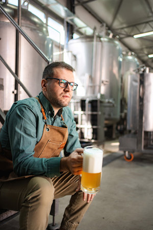 Man brewer tasting craft beer in modern brewery