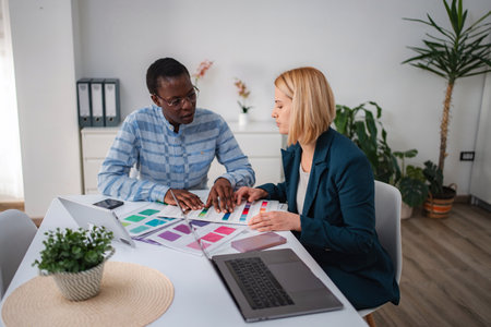 Diverse colleagues discussing color palettes for creative design projectの写真素材