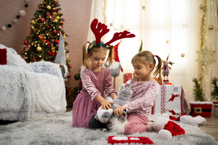 Two little girls playing with christmas plushie in decorated living roomの写真素材