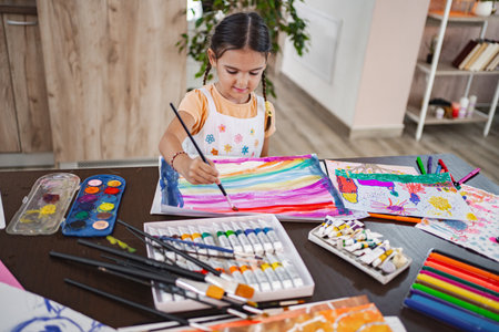 Cute girl joyfully painting colorful artwork in a bright living room during the afternoon