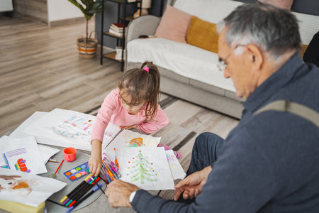 Grandfather and granddaughter share creative moments at homeの写真素材