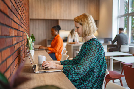 Woman Sitting at Table Using Laptop Computerの写真素材