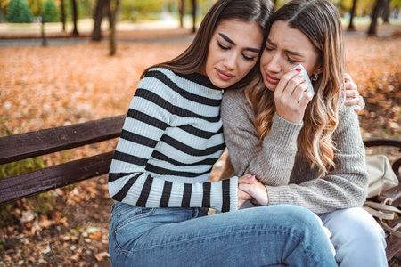 Girls sharing a heartfelt moment of love and support in a cozy autumn parkの写真素材