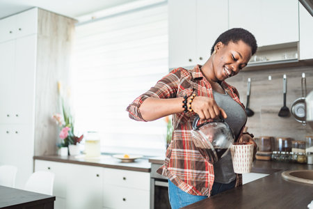 Young woman pouring coffee in her kitchenの写真素材