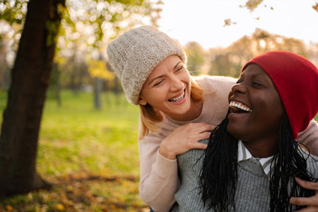 Diverse women friends laughing together enjoying autumn parkの写真素材
